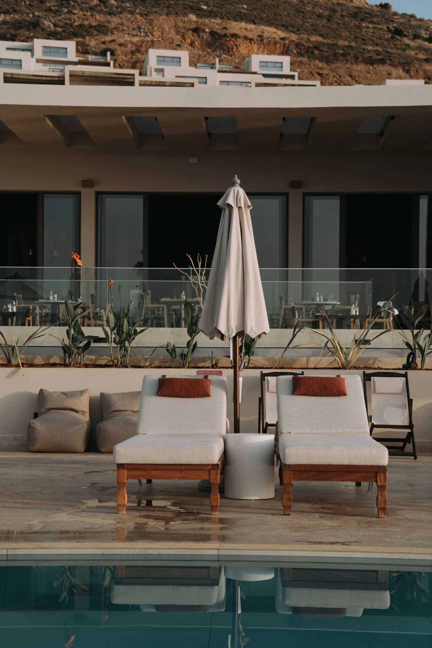 Deux bains de soleil et un parasol au bord d’une piscine